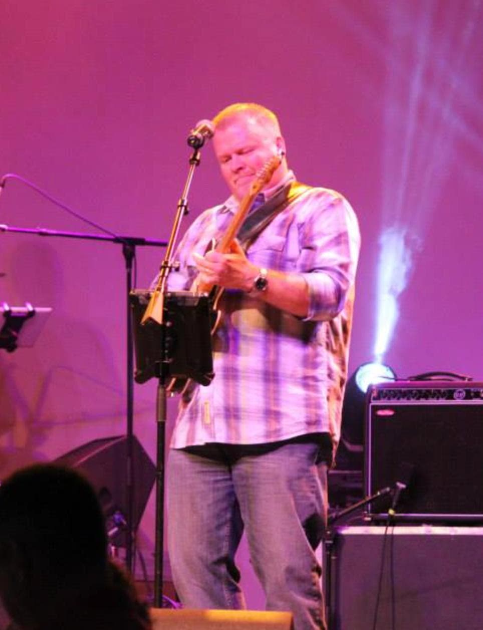 Kevin Blom playing electric guitar onstage under purple lighting